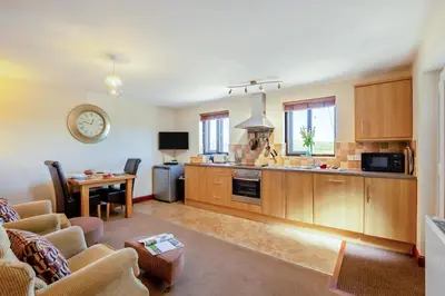 a kitchen with wooden cabinets and a living room at 1 Bed in Isel oc-b32075 in Sunderland