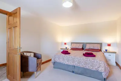 a bedroom with a large bed and a chair at 3 Bed in Isel oc-o32074 in Sunderland