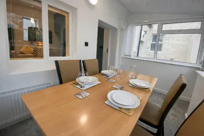 a wooden table with plates and wine glasses on it at The Croft in Ramsey