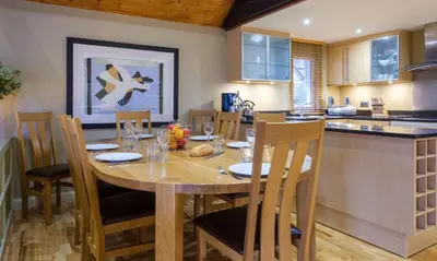 a kitchen and dining room with a wooden table and chairs at Grisedale in Applethwaite