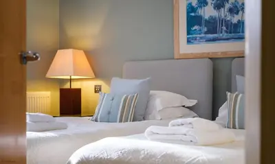 two beds in a hotel room with towels on them at Underscar - High Spy in Applethwaite