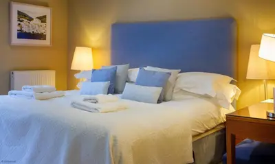 a large bed with white sheets and pillows on it at Underscar - Seatoller in Keswick