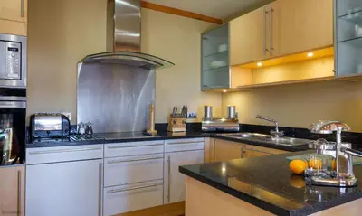 a large kitchen with white cabinets and black counter tops at Underscar - Great Gable in Keswick
