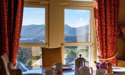 a dining room with a table and two windows at Underscar - Great Gable in Keswick