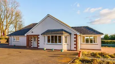 a small white house with a lot of windows at Rural luxury bungalow in Terreglestown