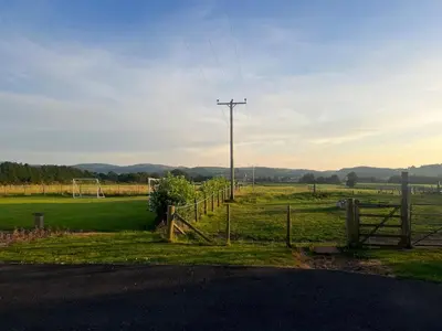 a farm with a fence and a field with a soccer field at Rural luxury bungalow in Terreglestown