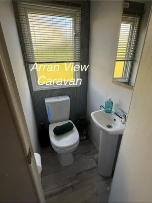 a bathroom with a white toilet and a sink at Arran View Caravan in Ayr