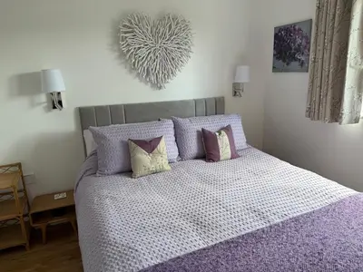 a bedroom with a large bed with purple sheets and pillows at Cliff Cottage Beautifully appointed apartment with world class view in Peel