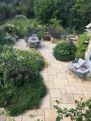 a patio with a table and chairs and flowers at Charming Cotswold stone cottage with garden in Moffat