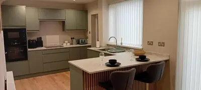 a kitchen with a island with two wine glasses on it at Martindale Close - 3 Bedrooms - Sleeps 5 in Whitehaven