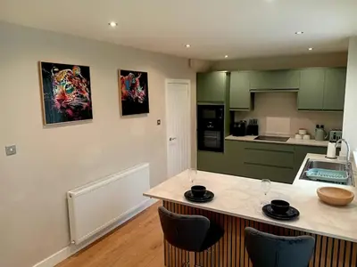 a kitchen with green cabinets and a counter with chairs at Martindale Close - 3 Bedrooms - Sleeps 5 in Whitehaven