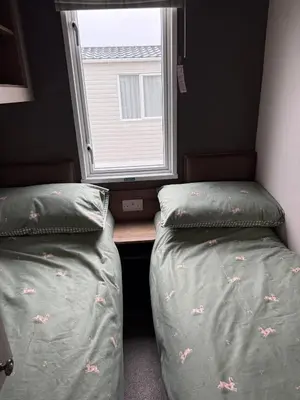 two beds in a small room with a window at Paws A While in Mainsriddle