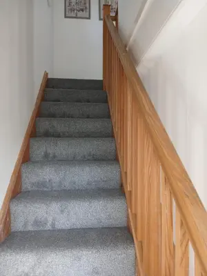 a staircase with wooden railings and gray carpet at Fabulous 4 Bed House in Leiston in Moffat