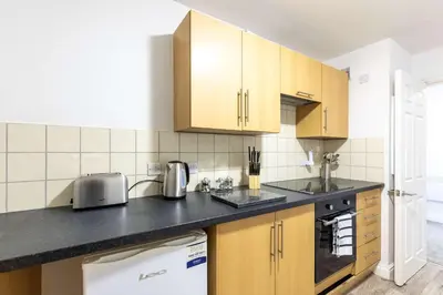 a kitchen with wooden cabinets and a black counter top at 1 Bed Whitehaven Harbour-side Flat with Sea Views in Whitehaven
