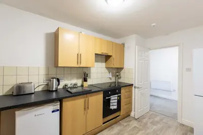 a kitchen with wooden cabinets and a black counter top at 1 Bed Whitehaven Harbour-side Flat with Sea Views in Whitehaven
