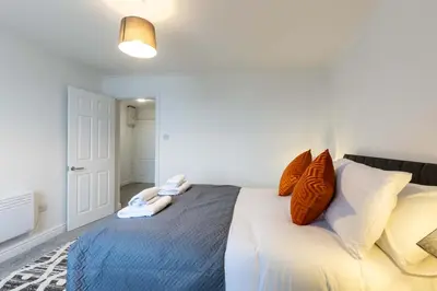 a bedroom with a bed with orange and white pillows at 1 Bed Whitehaven Harbour-side Flat with Sea Views in Whitehaven