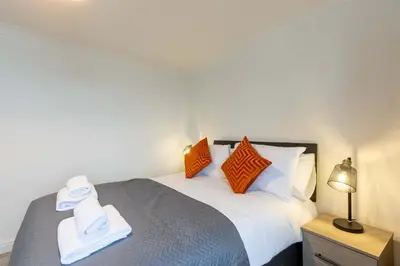 a bedroom with a bed with orange and white pillows at 1 Bed Whitehaven Harbour-side Flat with Sea Views in Whitehaven