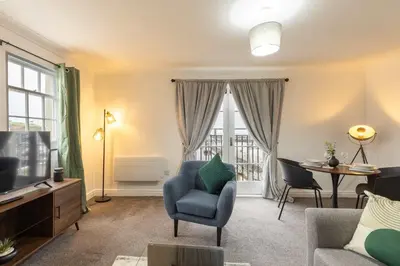 a living room with a blue chair and a television at Bright 1 Bed Harbour-side Apartment w Sea Views in Whitehaven