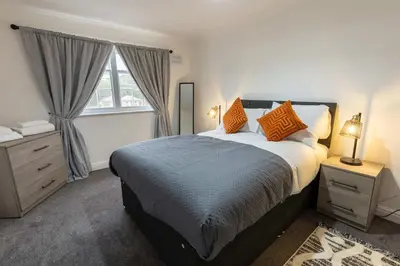 a bedroom with a bed with orange pillows and a window at Bright 1 Bed Harbour-side Apartment w Sea Views in Whitehaven
