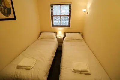 two beds in a small room with a window at Cedarfells, Hewetson Court, central Keswick with parking in Keswick