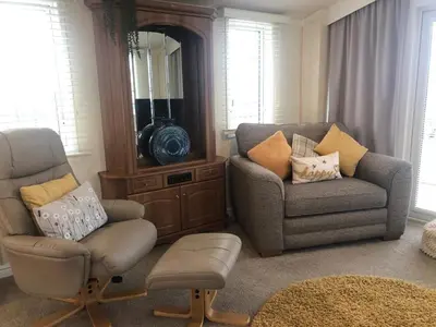a living room with a chair and a couch and a mirror at 29 The Beeches in Gilcrux