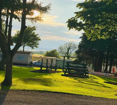 a park with benches sitting in the grass at 29 The Beeches in Gilcrux