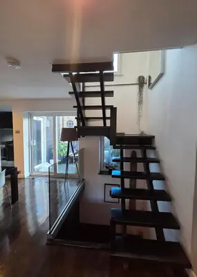 a wooden spiral staircase in a living room at Central London stylish 2-Bed House, with 2 terraces in Moffat