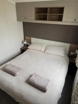 a bedroom with a white bed with two pillows on it at Paws a while in Mainsriddle
