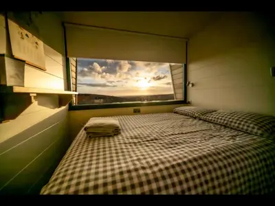 two beds in a room with a large window at Laverock How Shepherds Hut with private hot tub in Seascale