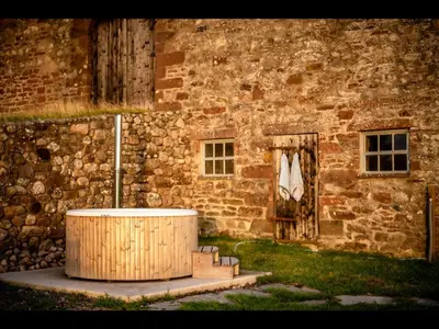 a building with a wooden barrel in front of a building at Laverock How Shepherds Hut with private hot tub in Seascale