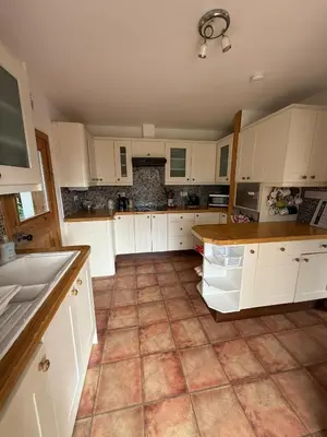 a large kitchen with white cabinets and a tile floor at Wee Knockinaam, Portpatrick - clifftop seaview in Portpatrick