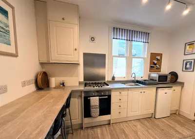 a kitchen with white cabinets and a stove top oven at Beautifully Presented Cosy Home in Kirkcudbright - Pass the Keys in Kirkcudbright