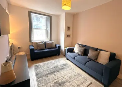 a living room with two blue couches and a window at Beautifully Presented Cosy Home in Kirkcudbright - Pass the Keys in Kirkcudbright