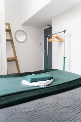 a bed with green sheets and a ladder in a room at Newton Flat in Carlisle