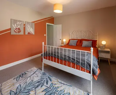 a bedroom with a bed with orange walls at 3 Bedroom house In Gloucester in Moffat