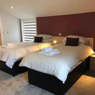 two beds with towels on top of them in a bedroom at Arrandale House in Douglas