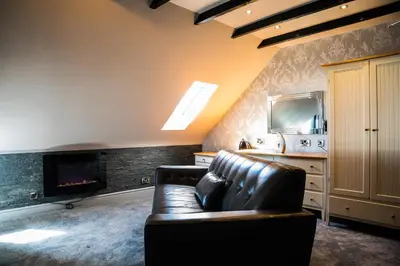 a living room with a leather couch and a fireplace at Mount Stewart Hotel in Portpatrick