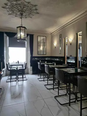 a dining room with tables and chairs and a chandelier at Mount Stewart Hotel in Portpatrick