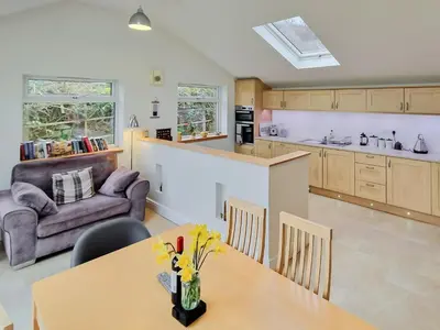 a kitchen and living room with a table and a couch at Bankswood Cottage in Ruthwell