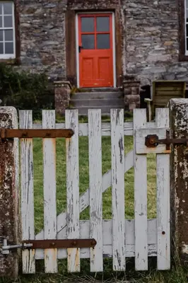 a white fence in front of a house with a red door at The Dash Farmhouse in Bassenthwaite