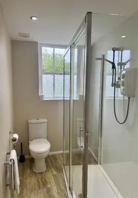 a bathroom with a toilet and a glass shower at The Manor in St Bees
