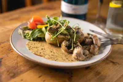 a plate of food with mushrooms and salad on a table at The Manor in St Bees