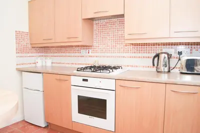 a kitchen with wooden cabinets and a white stove top oven at Wood Court, Troon in Troon