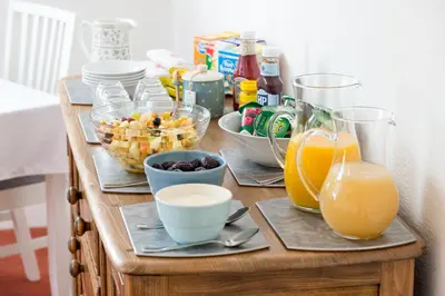 a wooden table topped with bowls of food and orange juice at Skiddaw Croft Bed & Breakfast in Keswick