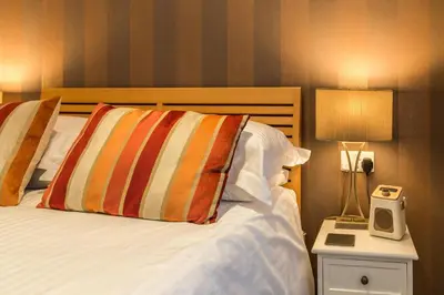 a hotel room with a bed and a night stand with a clock at Hermiston Guest House in Keswick
