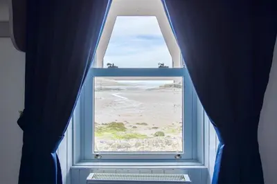 a window with a view of the beach and the ocean at The Harbour Inn in Garlieston
