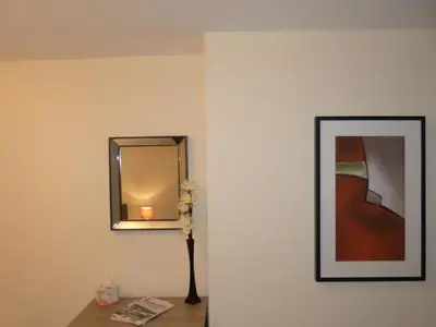 a mirror and a vase of flowers on a wall at The Sawmills, Carlisle - Spacious 4 Bedroom Family House - Free WiFi - & Parking - Walk to Carlisle Castle in Carlisle