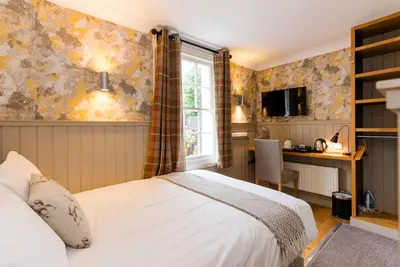 a bedroom with a bed and a desk and a window at The Harbour Guest House in Irvine