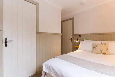 a bedroom with a white bed and a door at The Harbour Guest House in Irvine