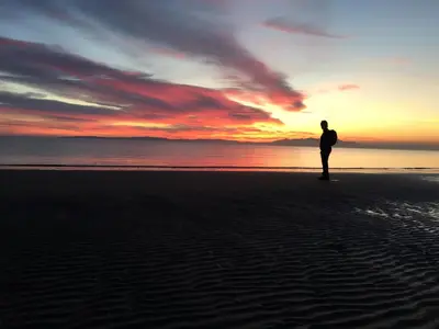 a person standing on the beach at sunset at The Harbour Guest House in Irvine